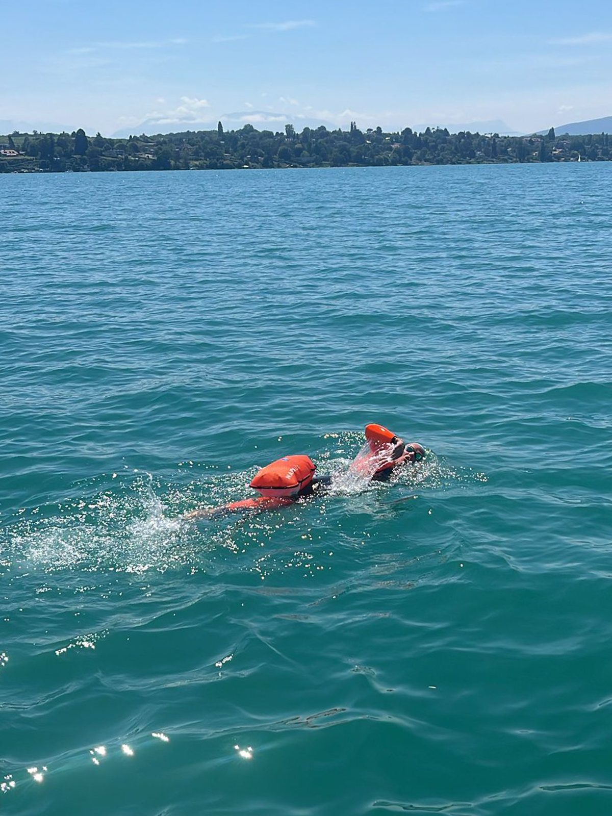 Chiara en crawl sur le Léman, bouée Restube orange, côte vaudoise au loin