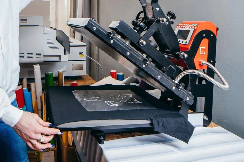 Presse à chaud appliquant un transfert sur un t-shirt dans l'atelier SKL Pub